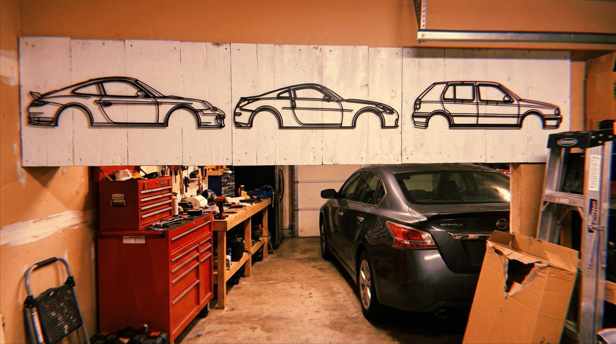 Three matte black steel car silhouettes hanging on the wall in a finished garage